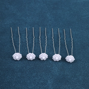 Detail of five white floral U-shaped hair pins with silver metal clips for bridal styling