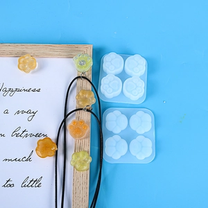 DIY mini cat paw silicone mold with resin charms in yellow and orange on blue background