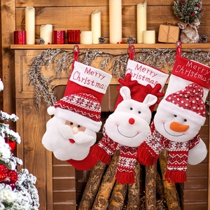 Three knitted Christmas stockings with Santa, reindeer, and snowman on a wooden fireplace
