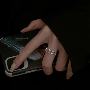 Close-up of double butterfly silver ring with small gemstones on a female hand