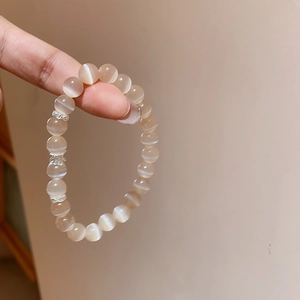 Détail macro d'un bracelet en œil de chat champagne avec des perles d'espacement argentées ciselées