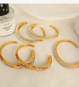 Detailed shot of gold plated open bracelets featuring white pearls and colorful zircons