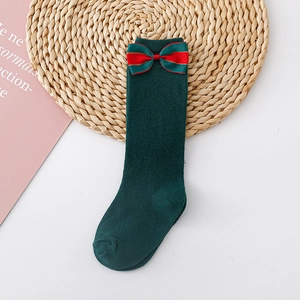 Detail of dark green cotton knee-high children socks with a large decorative bow