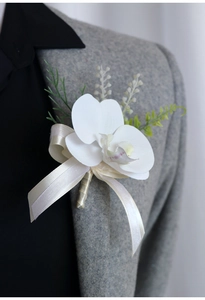 Close-up of white orchid boutonniere with beige ribbon on grey suit lapel for weddings