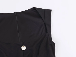 Detailansicht vom schwarzen Jumpsuit-Ausschnitt mit Strassknopf und Rückenreißverschluss