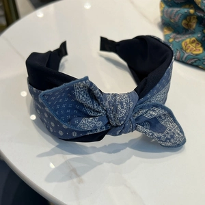 Détail d'un serre-tête bleu marine à motif paisley sur marbre montrant la texture du tissu