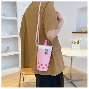 Detail shot of pink bubble tea shaped crossbody bag worn in a modern cafe setting