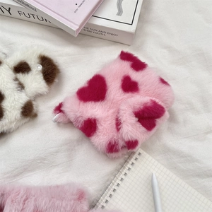 Detailed shot of a plush pink heart-patterned pouch on a white background with stationery