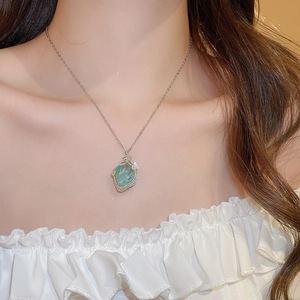 Detailed view of bohemian green raw stone pendant with gold wire wrapped on fine chain