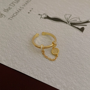 Macro detail of a gold butterfly ring with white enamel and a sparkling zircon pendant