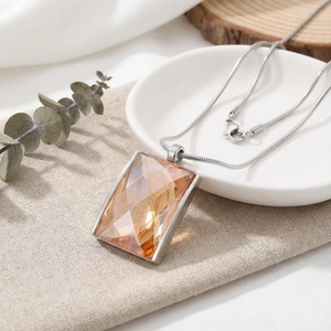 Close-up of champagne amber crystal pendant on a 18K gold-plated snake chain
