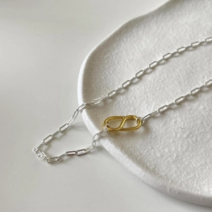 Close-up of a two-tone 925 silver rectangular chain necklace with a gold S-shaped link