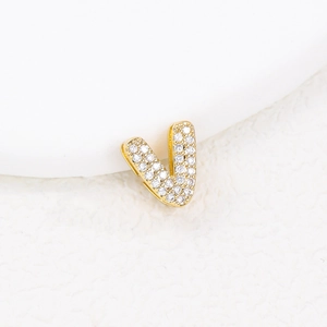 Macro view of a gold letter V pendant encrusted with sparkling cubic zirconia crystals