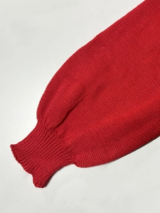 Primer plano de jersey de punto rojo con puños acanalados y detalle de costura fina
