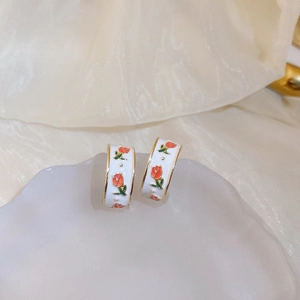 Détail des boucles d'oreilles tulipe vintage en résine sur un socle en pierre