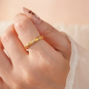 Close-up of vintage brushed gold twisted ring with small diamonds on a finger