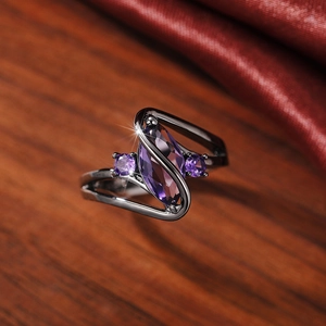 Macro shot of marquise-cut purple stone and gun black S-shape crossed band ring