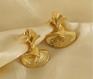 Close-up of golden stud earrings with twisted fan shape and hammered metal texture