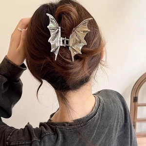 Silver metal bat wing hair claw clip for women shown on a stylish bun hairstyle