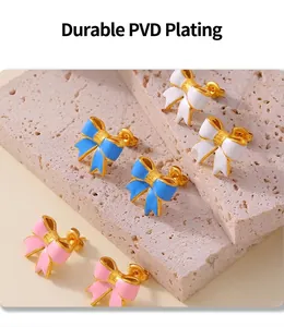 Dettaglio di orecchini a fiocco colorati con smalto rosa, blu e bianco su oro PVD