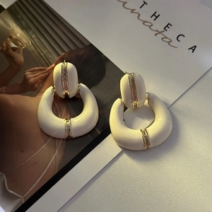 Detailed view of vintage French style cream enamel hoop earrings with gold metal accents