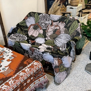 Close-up of woven camping blanket with floral patterns and fringes on an outdoor sofa