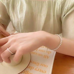 Close-up of minimalist 2mm sterling silver bead bracelet and ring on a hand