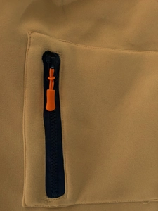 Detail eines schwarzen Reißverschlusses und orangefarbenem Kordelzug auf gelbem Hoodie