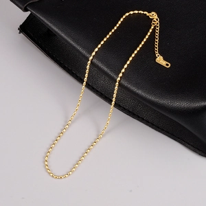 Detail of 18K gold beaded necklace with extension chain and K18 hallmark on black leather