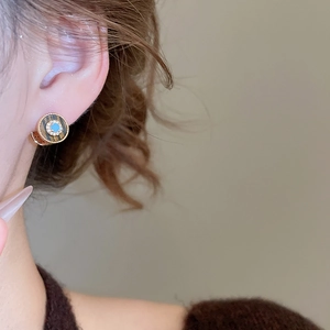 Detailaufnahme von 18K vergoldeten Ohrringen mit Zirkon und Türkis am Modell getragen