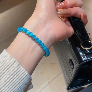 Macro detail of blue cat-eye stone beads on elastic bracelet with shimmering light bands