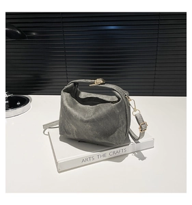 Detail of vintage gray canvas shoulder bag with metallic buckle on a decorative book