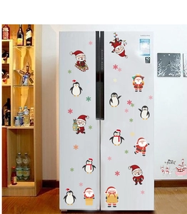 Detailed view of Santa and penguin Christmas stickers on a white refrigerator door
