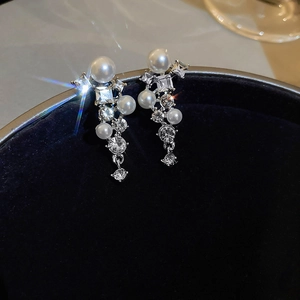 Macro shot of silver pearl tassel earrings with rhinestones on dark velvet base