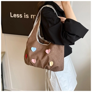 Détail du sac seau en daim marron avec cœurs 3D colorés et bordure argentée brillante