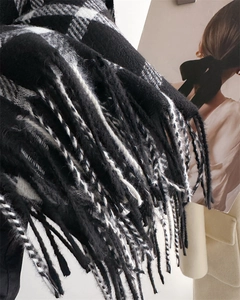 Detailed close-up of thick monochrome plaid scarf tassels and soft cashmere-like texture