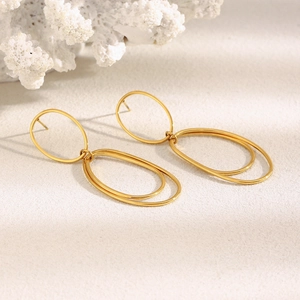 Detail of 18K gold-plated double-loop earrings on white coral showing premium texture