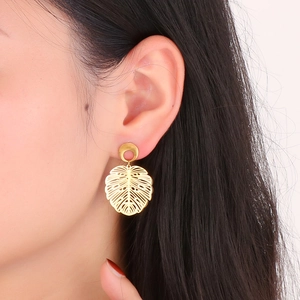 Close-up of a 18K gold-plated stainless steel monstera leaf earring worn by a model