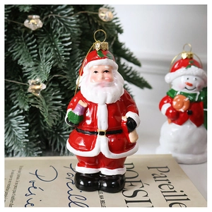 Detail of painted Santa Claus ornament with gold hook on vintage books background