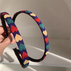 Detail view of navy blue headband featuring red, yellow and green embroidered hearts