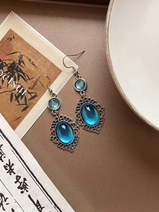 Macro shot of vintage lace silver earrings with oval navy resin pendants on art paper