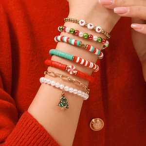 Gros plan de sept bracelets de Noël superposés avec perles colorées et breloques