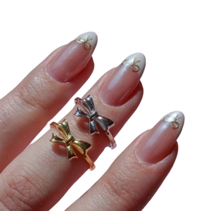 Bow tie rings in gold and silver plating shown on hand with 18K gold finish design
