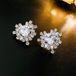 Detail shot of heart-shaped zircon earrings with radiant cut stones on a black background