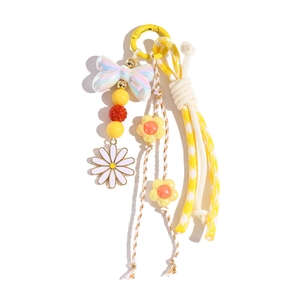 Détail du porte-clés marguerite jaune avec perles, nœud et corde à carreaux