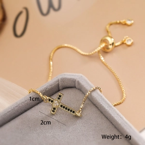 Macro detail of a 18K gold plated cross bracelet with black and clear cubic zirconia