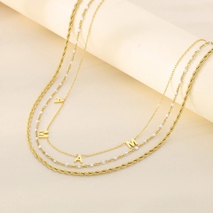 Detailed view of layered gold MAMA letter necklace with beads and twisted rope chain