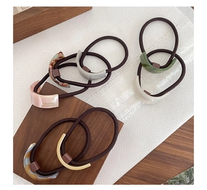 Detail of minimalist acetate hair ties with gold accents and geometric curved designs