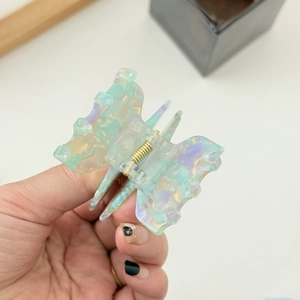 Macro detail of butterfly hair claw clip with marble texture acetate and gold spring