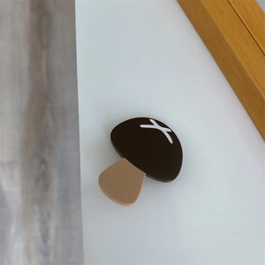 Close-up of a brown mushroom acetate hair clip featuring a white cross pattern